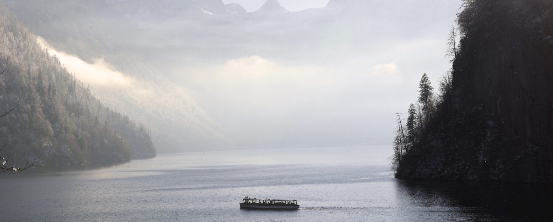 Königssee im Winter mit Ausflugsboot vor verschneiter Bergkulisse – beliebtes Winter-Ausflugsziel im Berchtesgadener Land und in der Region Salzburg.