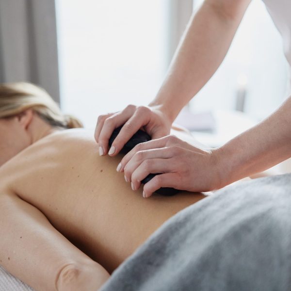 Eine Frau erhält eine Massage auf ihrer Schulter in einem hell erleuchteten Raum.