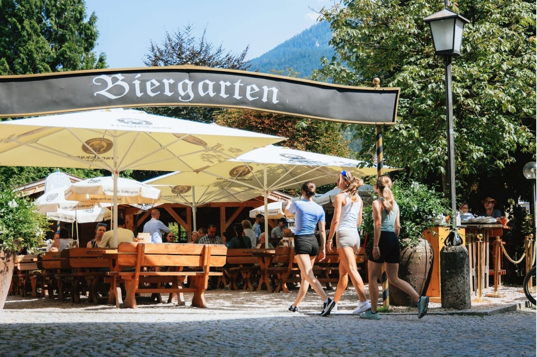 Biergarten des Gasthof Neuhaus in Berchtesgaden mit Gästen unter Sonnenschirmen im Sommer