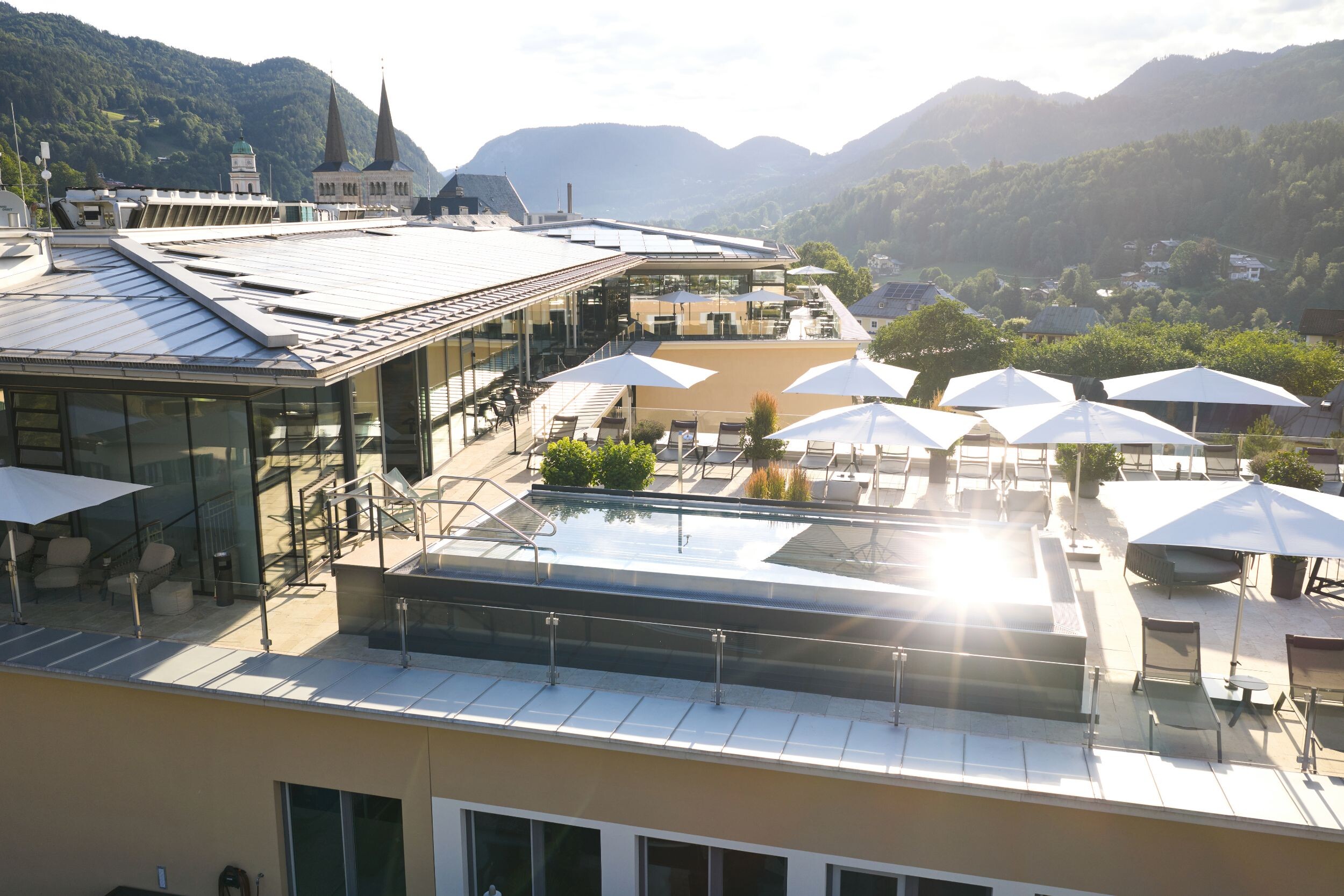 Pool und Sonnenterrasse des Hotel EDELWEISS Berchtesgaden mit Blick über Berchtesgaden und die umliegenden Berge.