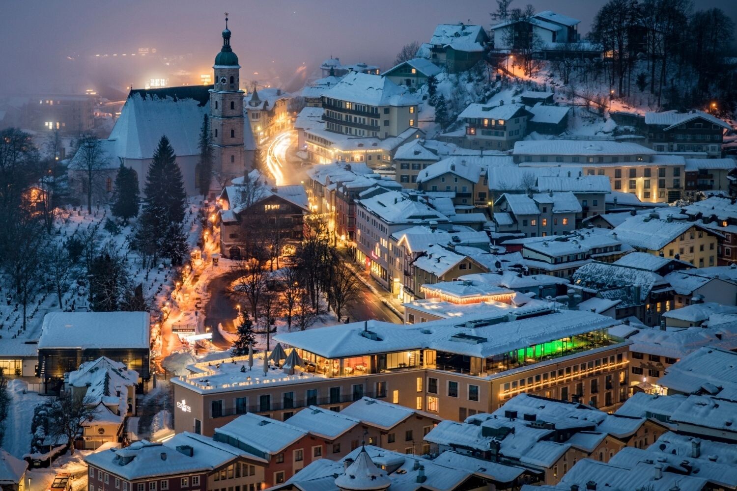 Winterliche Luftaufnahme des Hotel EDELWEISS Berchtesgaden im verschneiten Ortszentrum mit festlicher Beleuchtung und Blick auf die Stiftskirche.