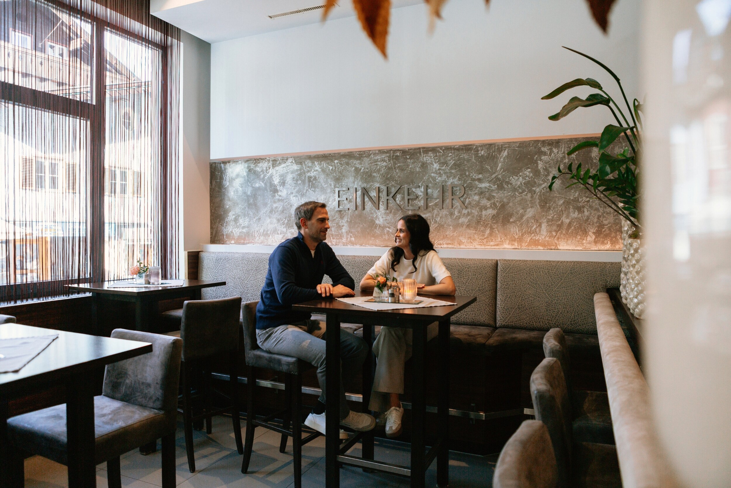 Paar sitzt im Restaurant Einkehr in Berchtesgaden am Tisch und genießt mediterrane Gerichte in gemütlicher Winteratmosphäre