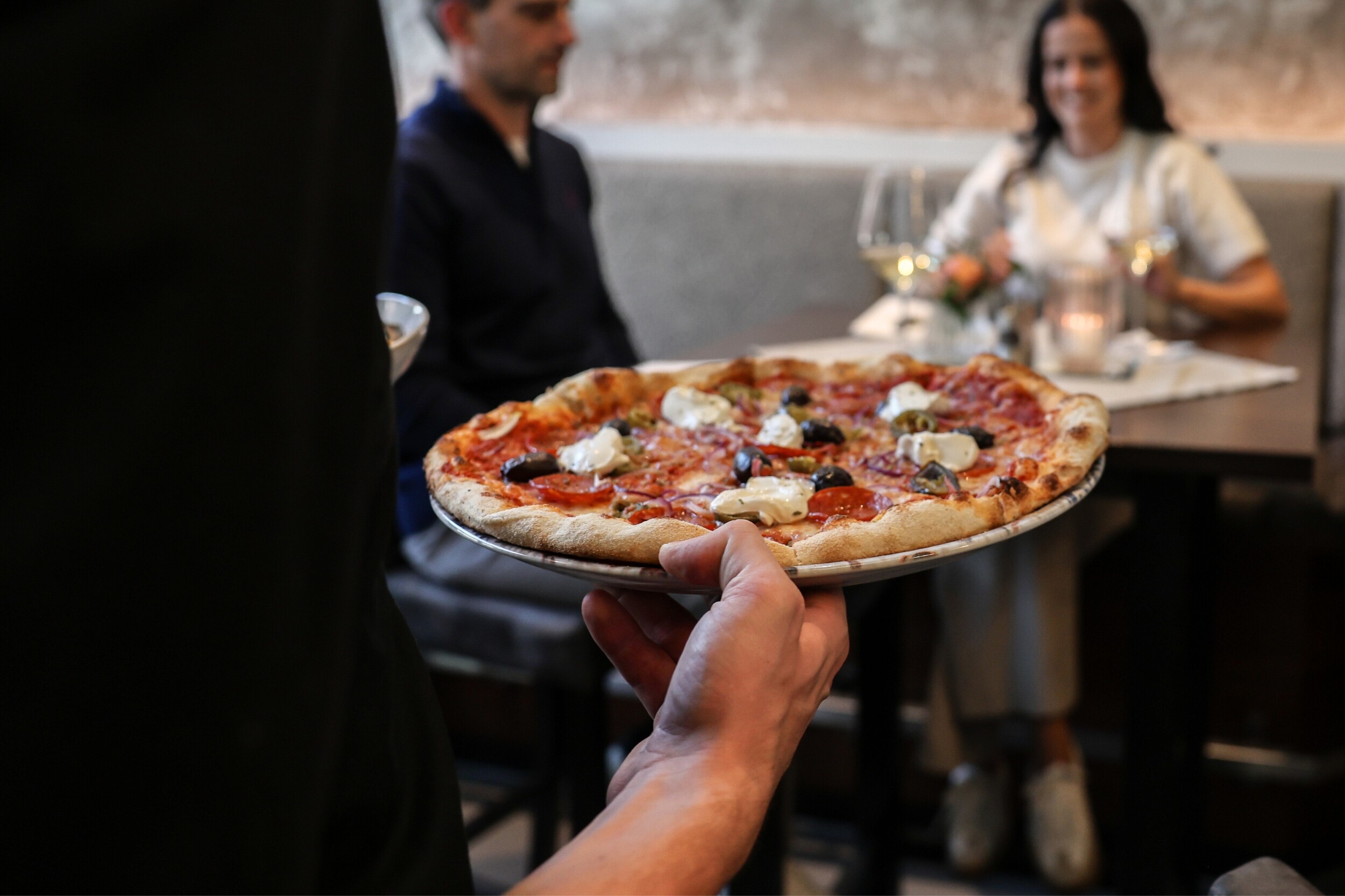 Frisch gebackene Pizza aus dem Steinofen im Restaurant Einkehr in Berchtesgaden, serviert in gemütlicher winterlicher Atmosphäre