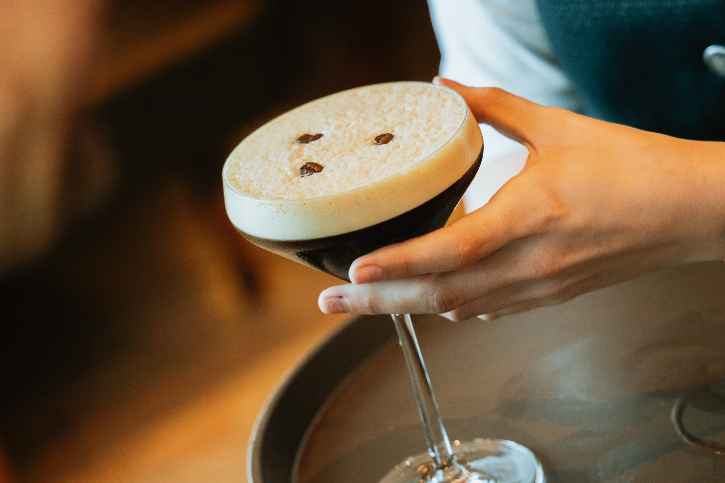 Espresso Martini wird an der Bar im Hotel EDELWEISS Berchtesgaden serviert, cremiger Cocktail mit Kaffeebohnen als Garnitur für stilvolle Genussmomente