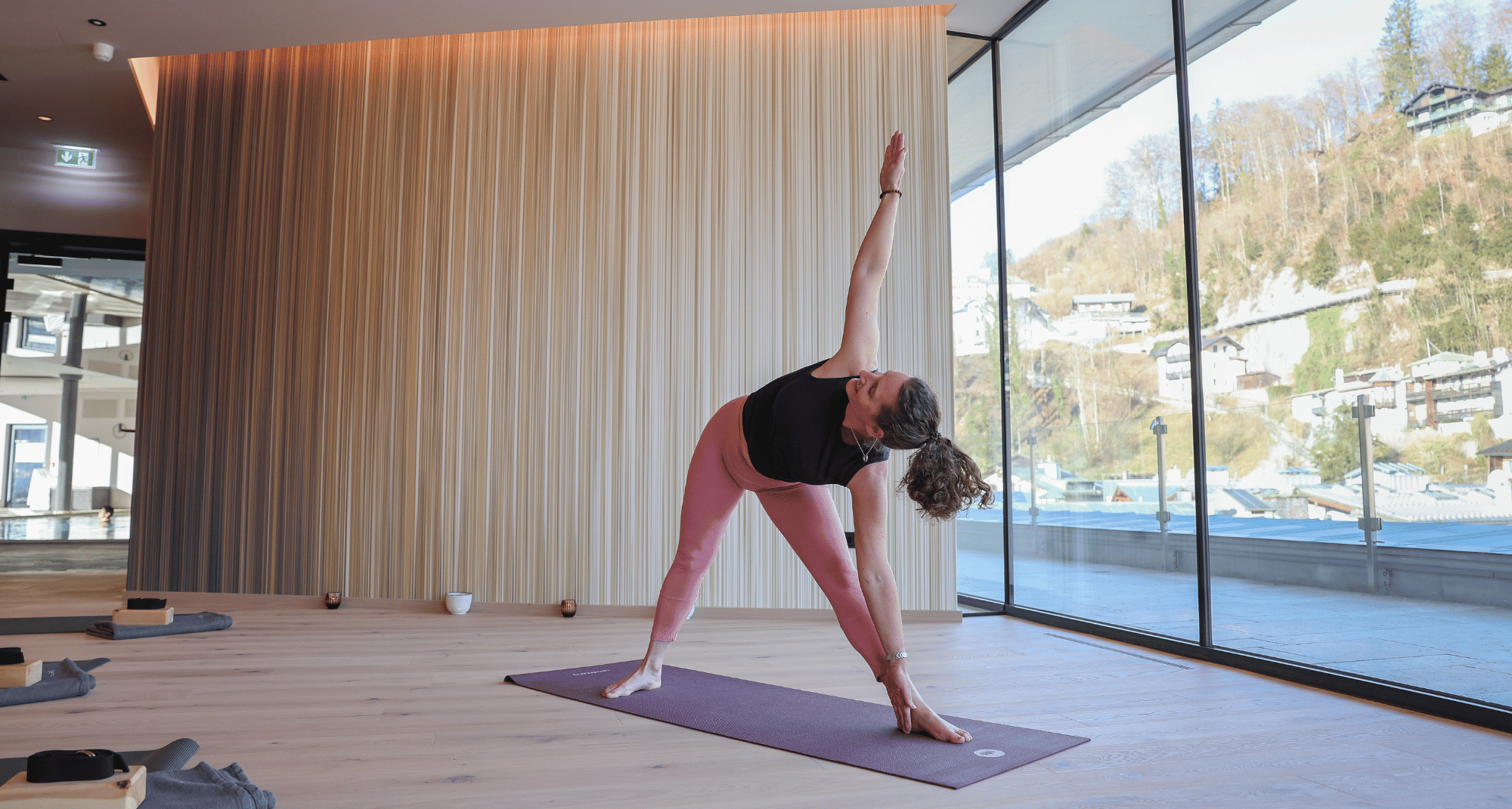 Woman practicing yoga in a bright studio at Hotel EDELWEISS Berchtesgaden with panoramic views, promoting relaxation, mindfulness and balance during a wellness holiday in Bavaria